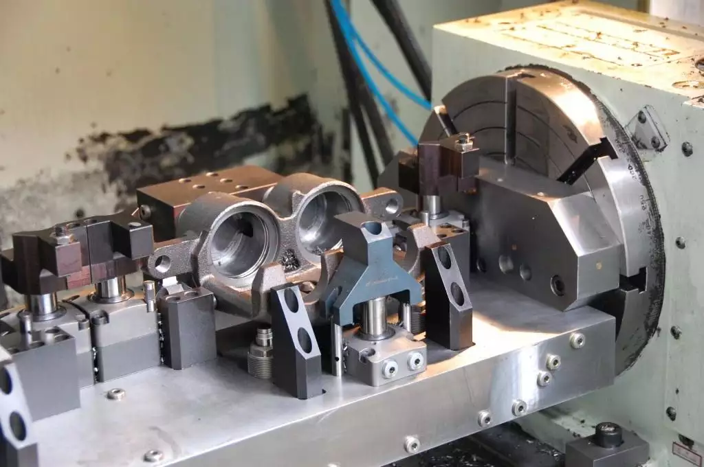 Tutto quello che c'è da sapere sulla lavorazione CNC a 4 assi 3 A 4-axis CNC machining center using a rotary axis to machine multiple sides of a workpiece in a single setup. The image highlights how 4-axis machining reduces repositioning, improves production efficiency, and helps lower manufacturing costs for complex precision components.